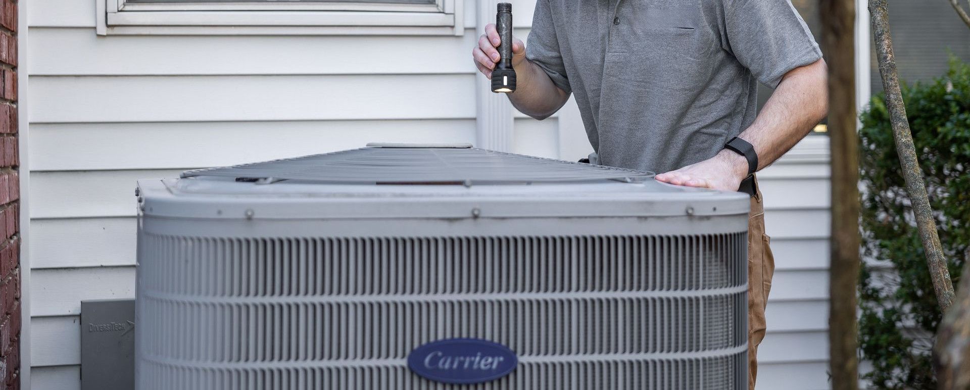 A technician inspects an outdoor HVAC unit for maintenance.